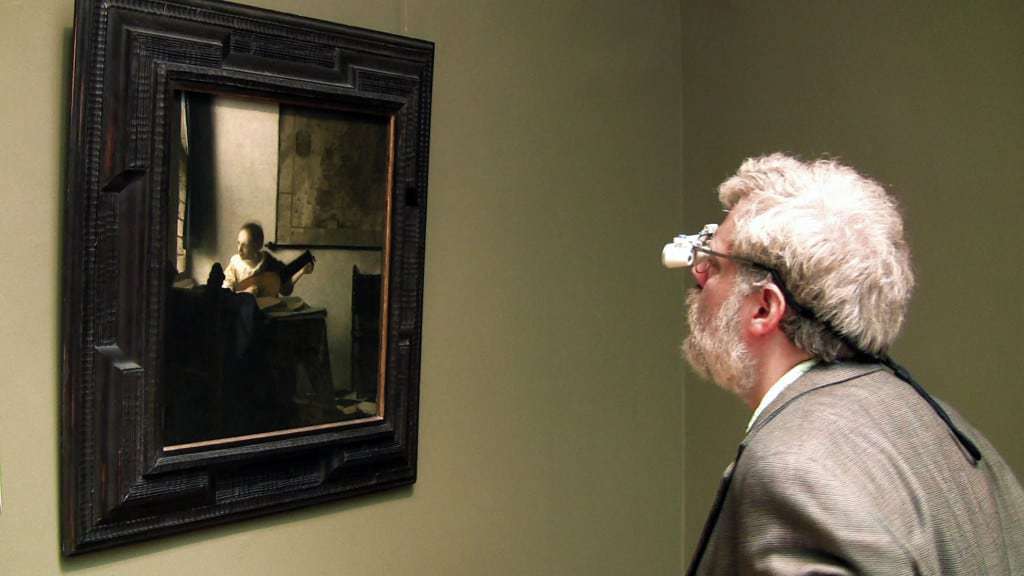 Tim Jenison, wearing his surgical loupes, inspects Johannes Vermeer’s “Woman with a Lute” at the Metropolitan Museum of Art in New York. Photo by Shane F. Kelly, © 2013 High Delft Pictures LLC, Courtesy of Sony Pictures Classics. All Rights Reserved. 