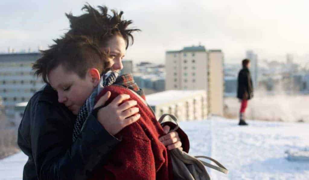 Two girls hug on a snow-covered rooftop in a still from the film.