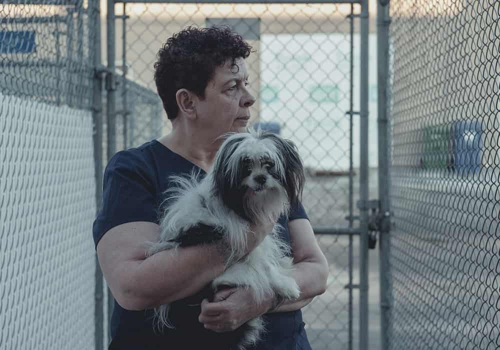 Shan MacDonald holding a dog inside a kennel in Heather Young's Murmur