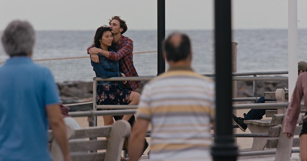 Isabel Sandoval as Olivia and Eamon Farren as Alex in Lingua Franca. The two characters are embracing by the sea.