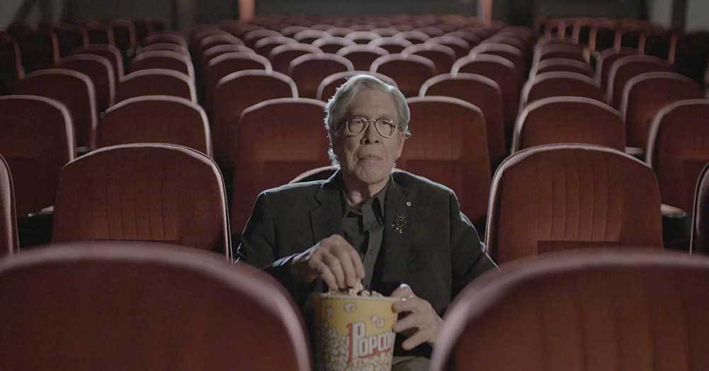 Thomas King sits in a movie theatre in Inconvenient Indian.