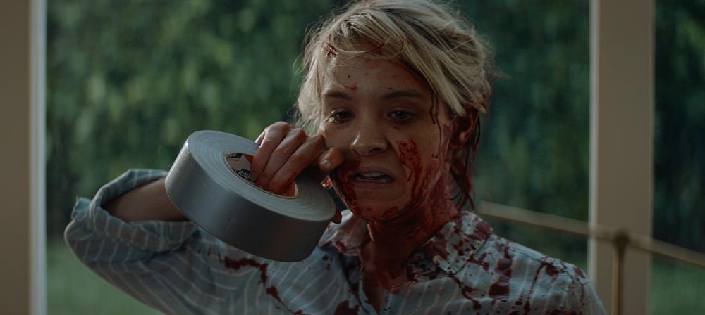 Brea Grant as May, wiping blood off her face after a fight with her stalker.