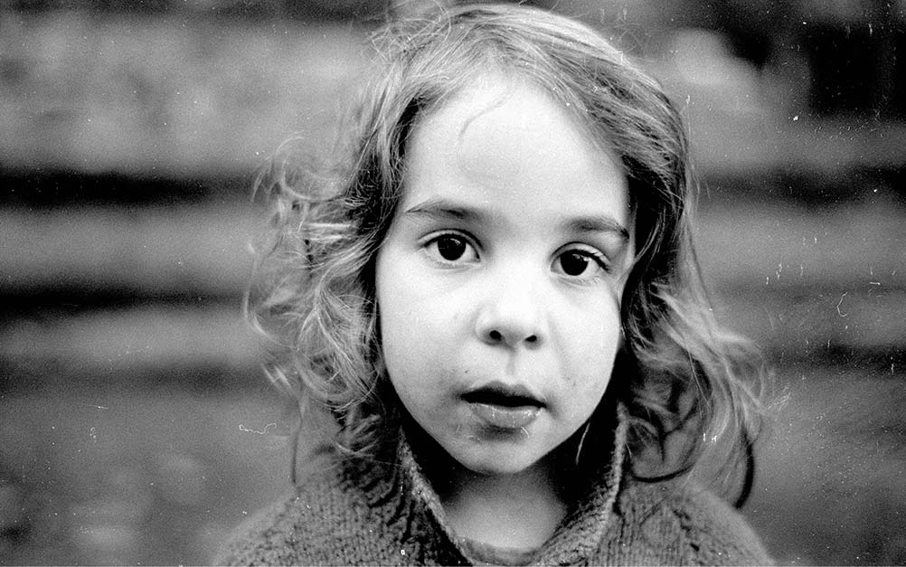A young girl looks into the camera lens in this black and white photo.