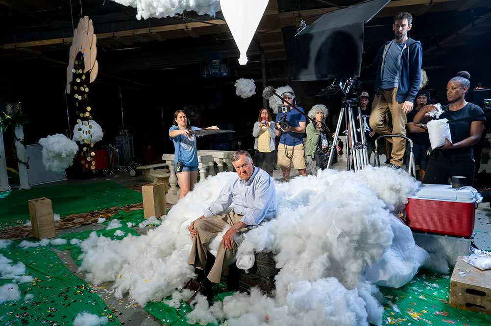 Dick Johnson sits amongst a mountain of cotton on a soundstage, surrounded by film crew.