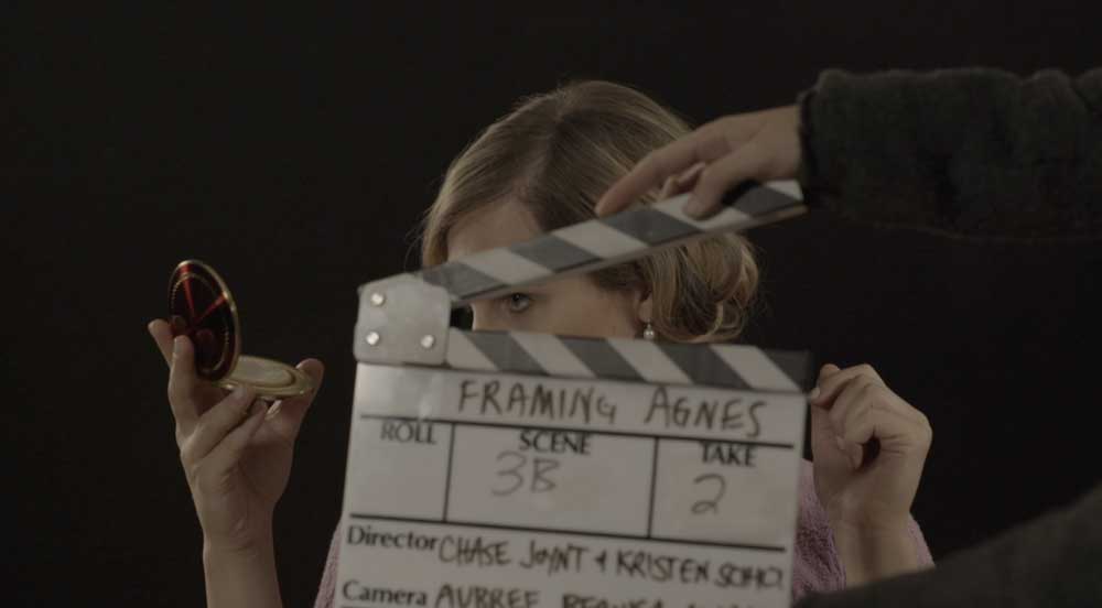 A filmmaker holds a clapperboard in front of actress Zackary Drucker's face. The clapperboard reads: Framing Agnes.