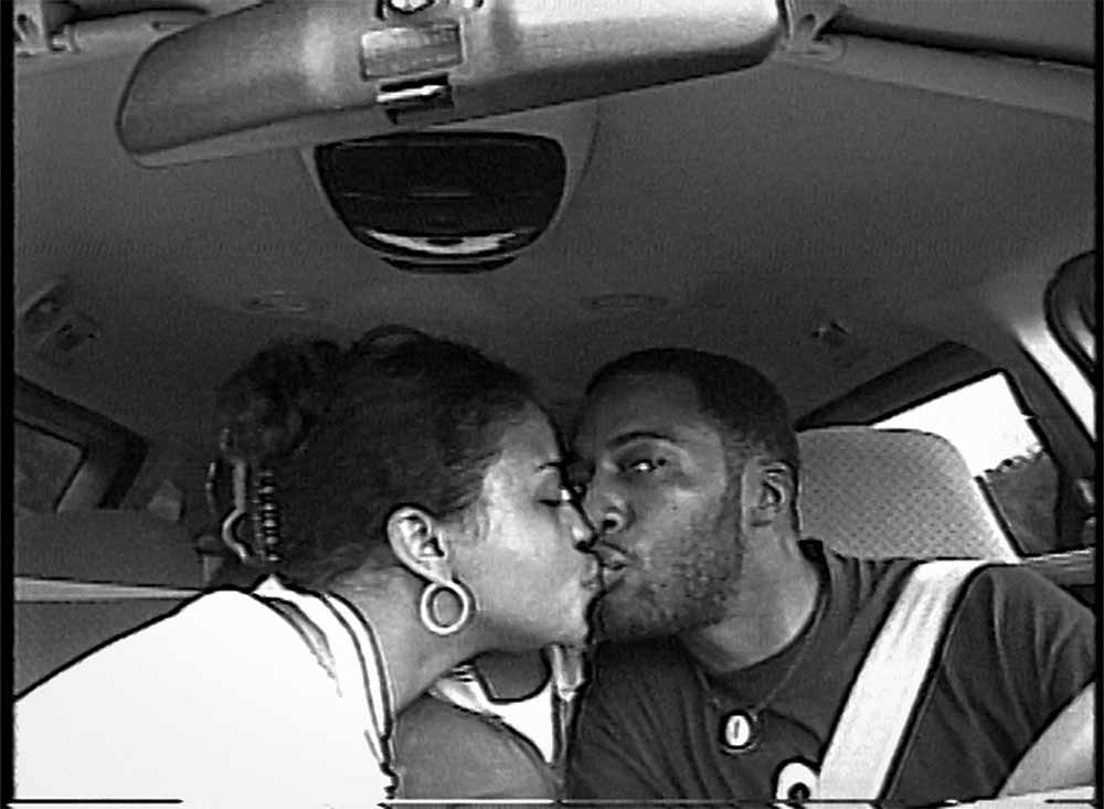 Fox Rich and her husband, Robert, kiss in their car in grainy black and white home video footage.