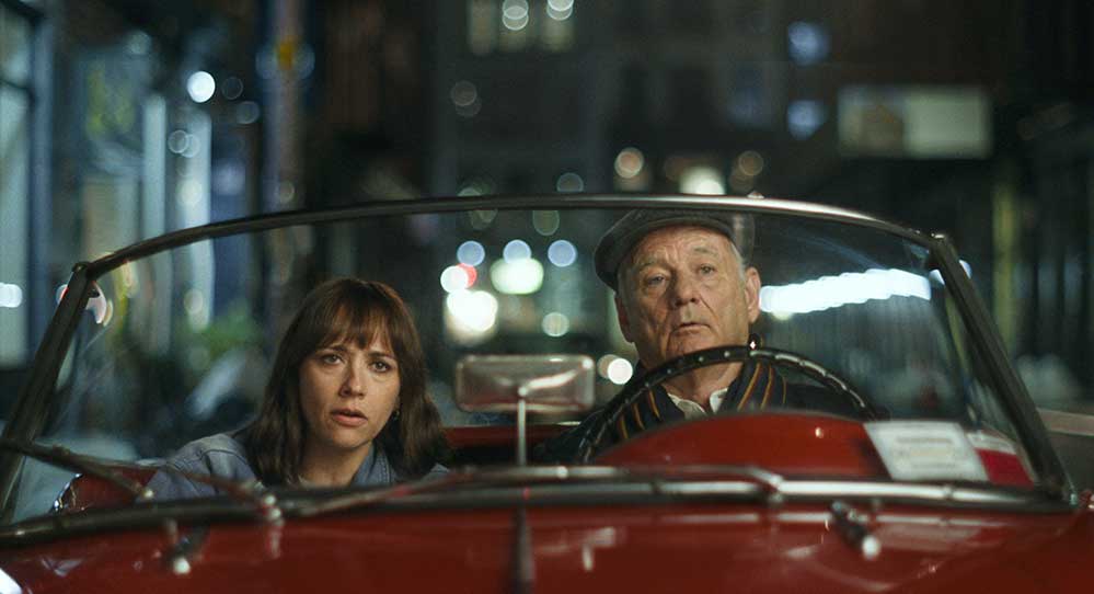 A woman and her father sit in an old fashioned car.