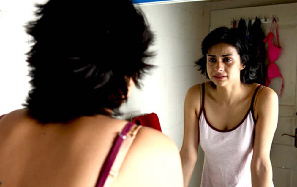 A woman in a vest looks at herself in the mirror, distraught, in Alankrita Shrivastava's film Turning 30.