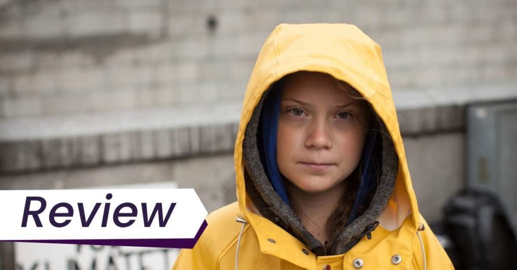 Greta Thunberg wears a yellow raincoat with hood on and looks into lens in Nathan Grossman's I Am Greta, courtesy of Mongrel Media.