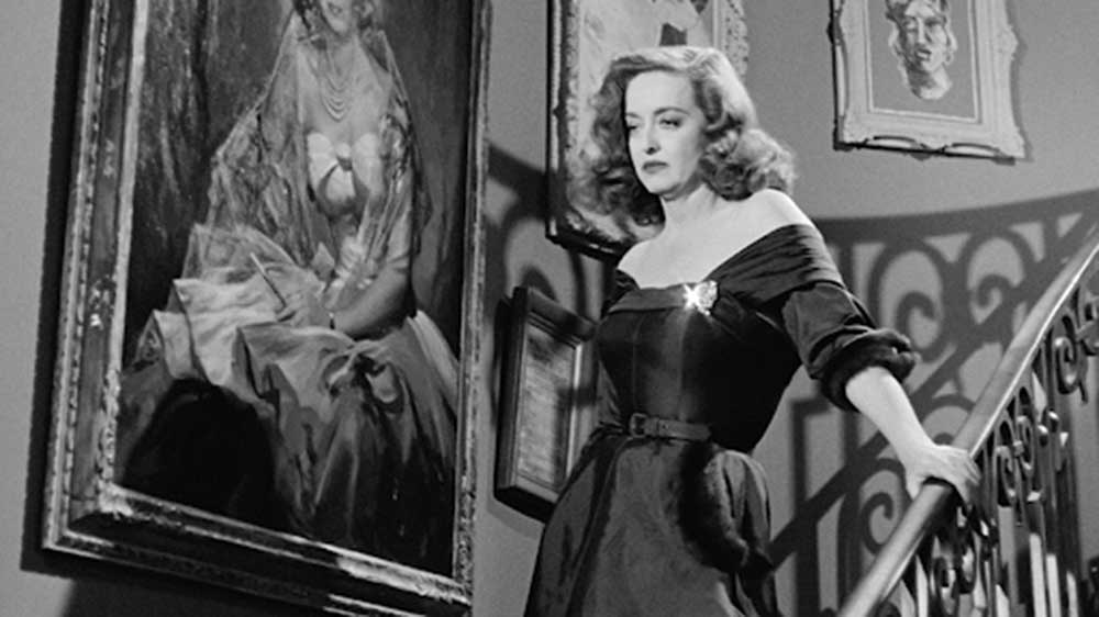 Bette Davis descends a staircase in this black and white still from the 1950 All About Eve.