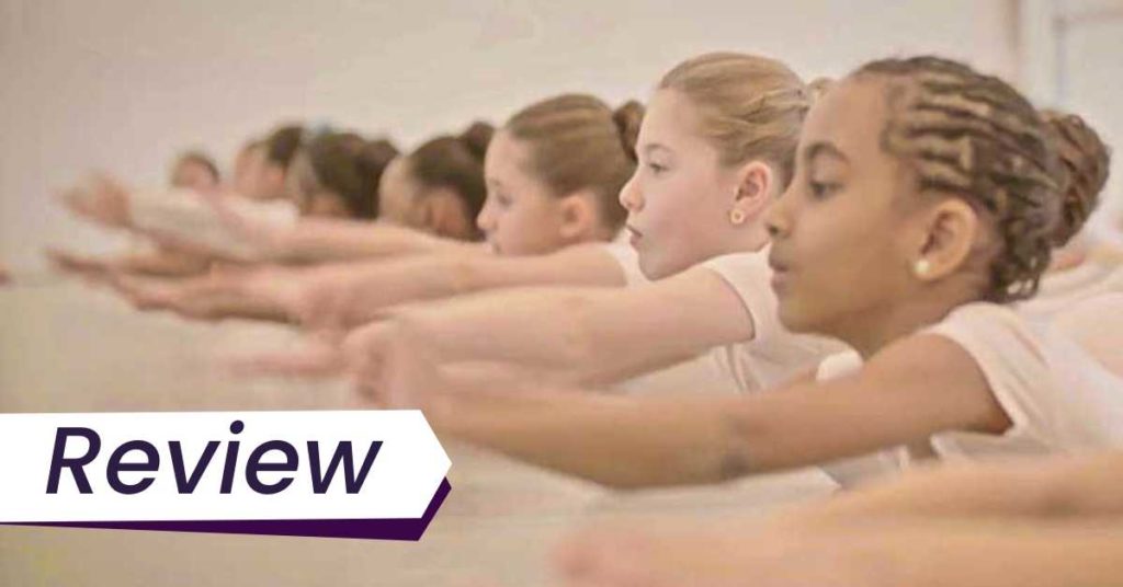 A row of children stretch their arms out in unison, in a dance class. The image is accompanied by the text, 'Review'.