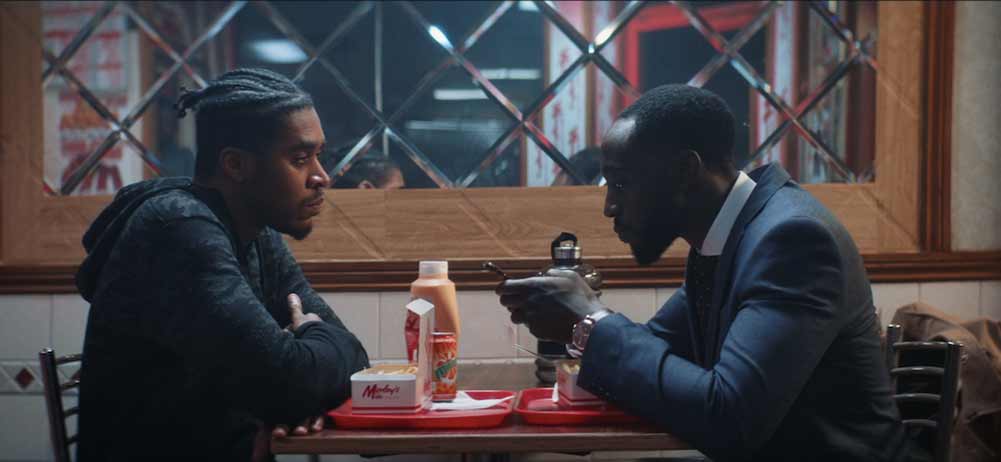 Two men chat over the table at a chicken shop in No More Wings.