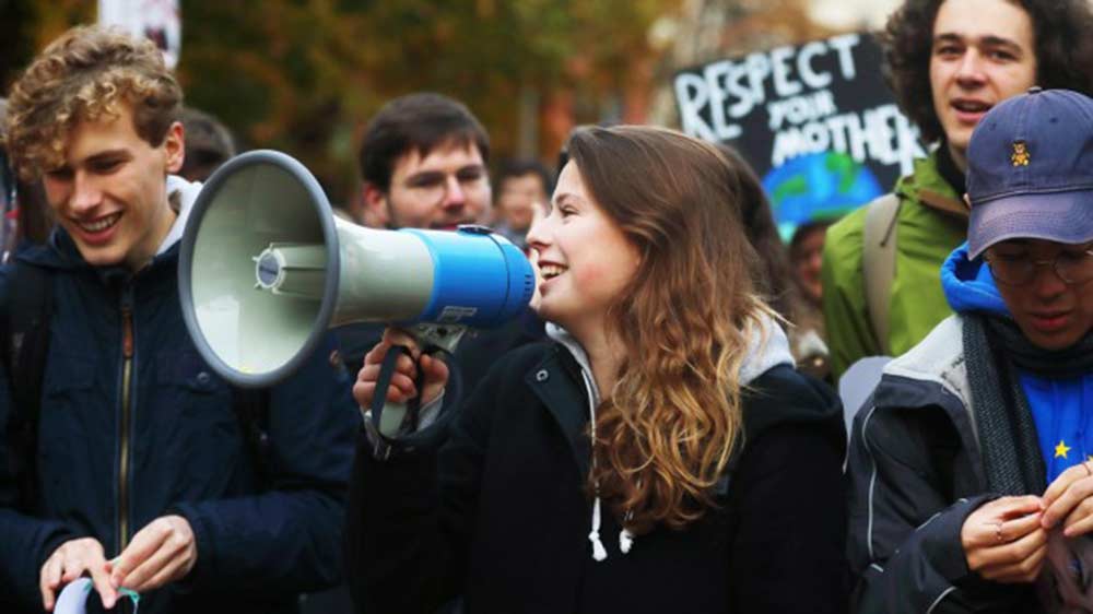 Young climate activist Luisa Neubeauer speaks into a megaphone at a protest in the documentary Now.