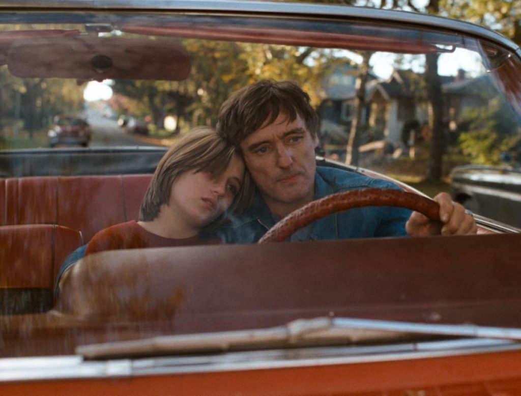 Still from Dennis Hopper's Out of the Blue, courtesy of Festival du Nouveau Cinema. Father and daughter are in a convertible; father is driving and has his arm around his teenage daughter who is leaning her head on his shoulder.