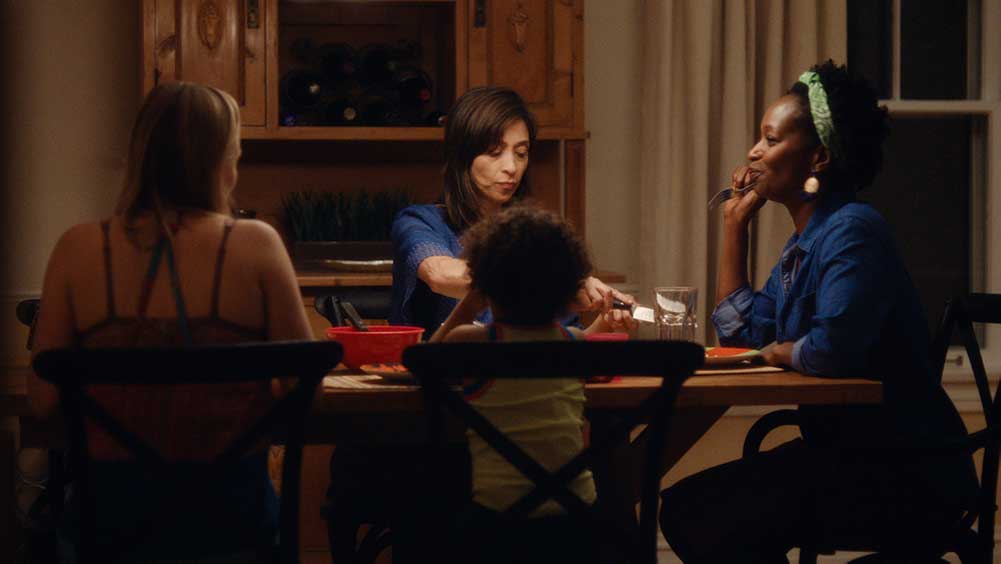 Four women sit around a dinner table, having a meal.