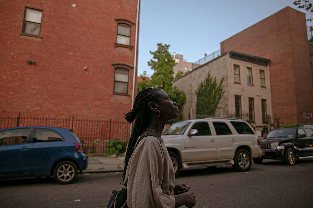 Esther walks around Brooklyn, looking up at the buildings around her on a quiet street.