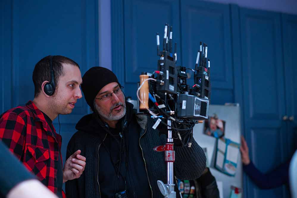 Brandon Cronenberg and cinematographer Karim Hussain lean together in discussion behind a camera on the set of Possessor.