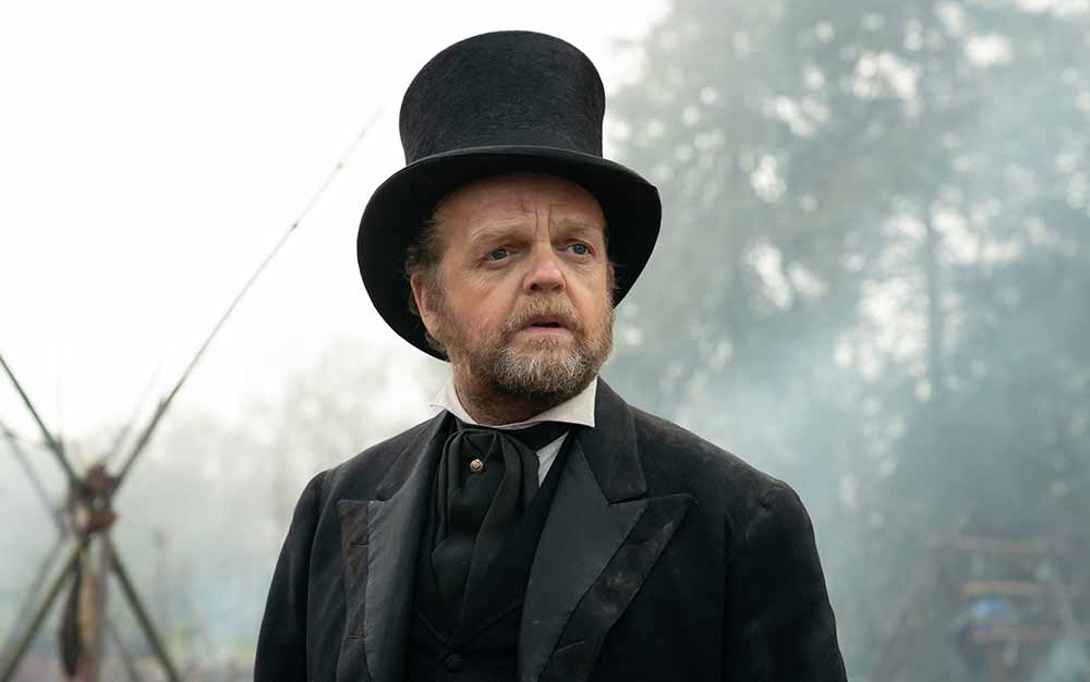 A closeup of Toby Jones in First Cow, wearing a fancy top hat and suit.