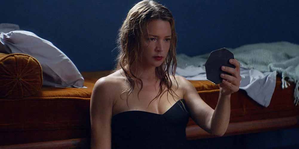 Virginie Efira holds a hand mirror up to her face in Sibyl.