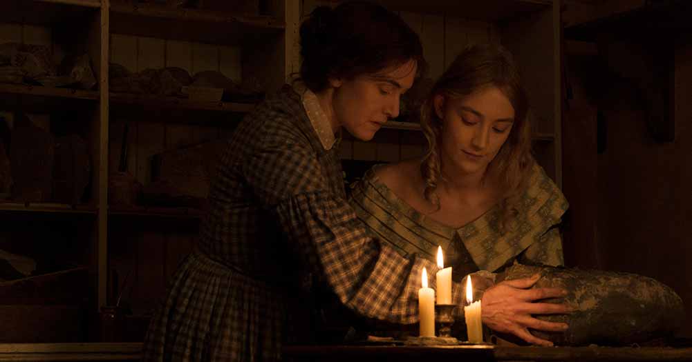 Two women lean together by candlelight in Ammonite, one of the best films of 2020.