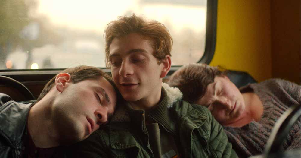 Three friends lean on each other at the back of a coach in And Then We Danced, one of the best films of 2020.