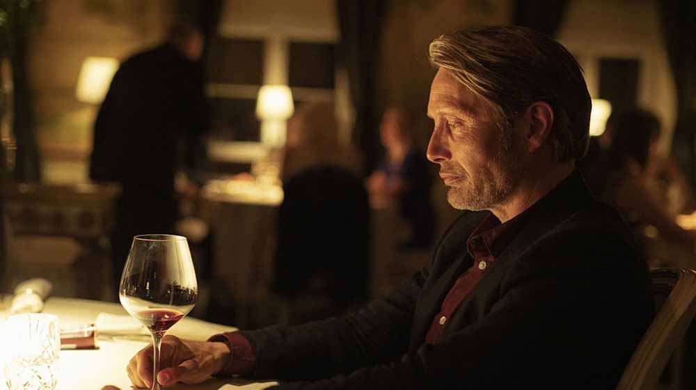 Mads Mikkelsen sits at a restaurant, staring into a wine glass, in Another Round, a film with some of the best sound design of 2020.