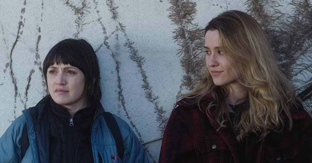 Two young women stand against a moss coloured wall in Fourteen, one of the best films of 2020.