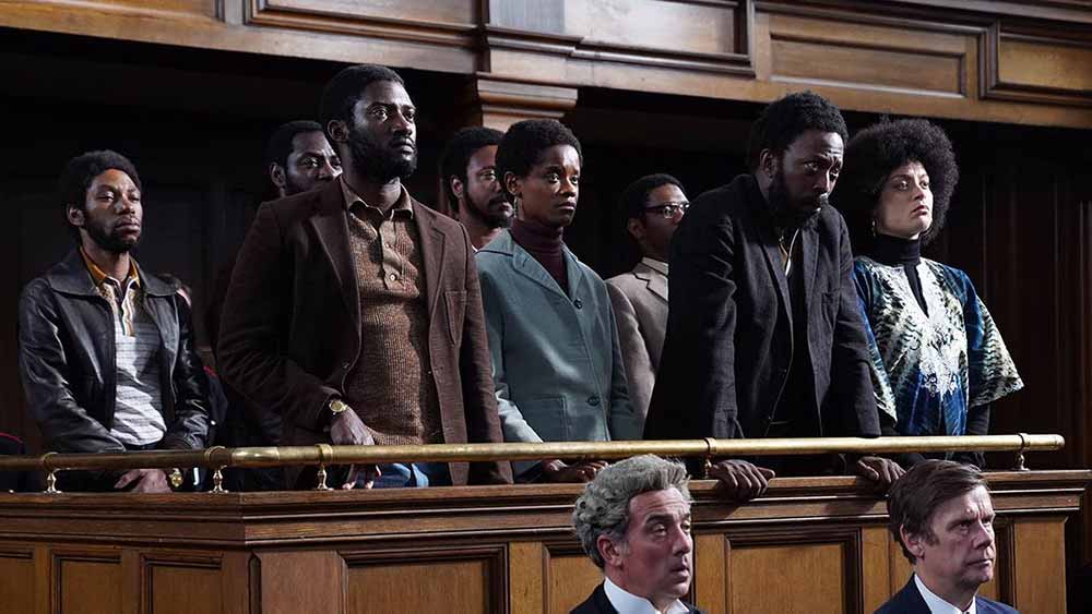 A group of defendants stand in a court box in Mangrove.