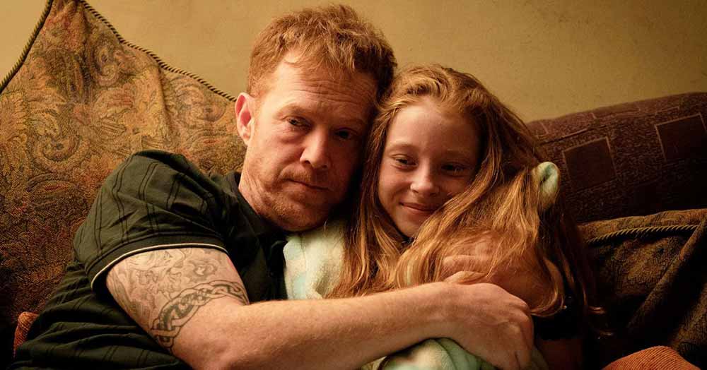 A father embraces his young daughter on the couch in Sorry We Missed You, one of the best films of 2020.