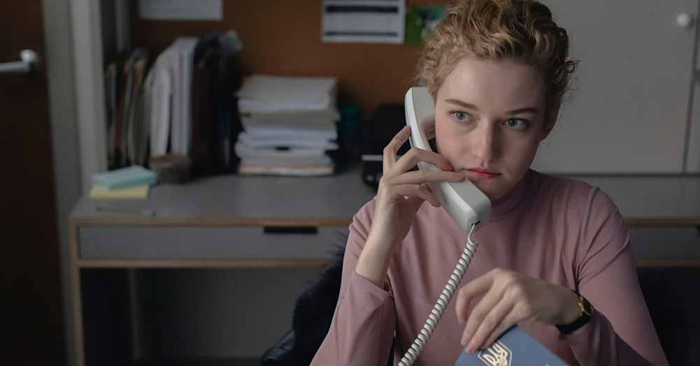 A young woman sits at an office desk, on the phone, in The Assistant.