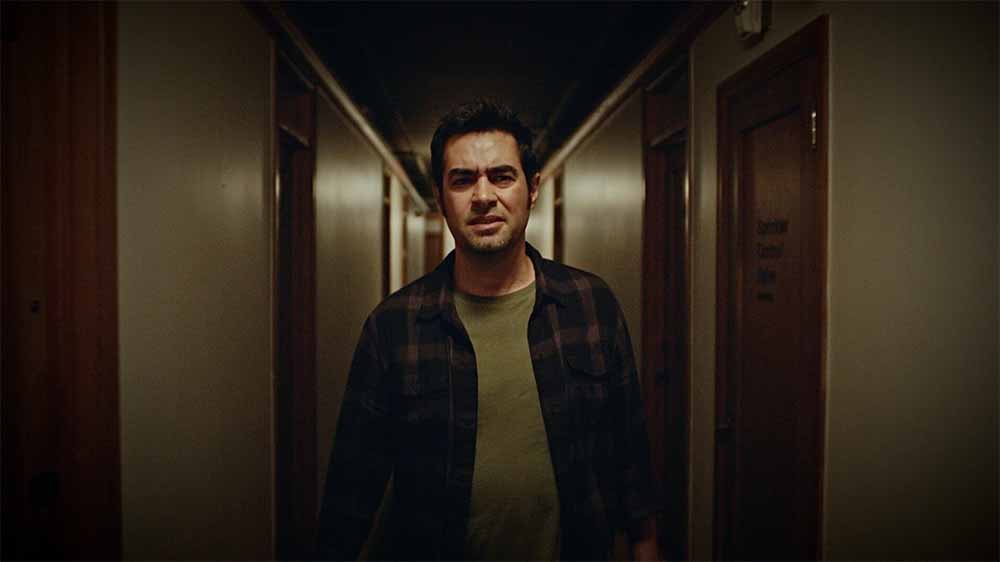Shabab Hosseini walks down a dark hotel corridor.