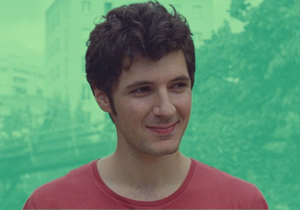 A still of Vincent Lacoste in Amanda, in front of a green background.