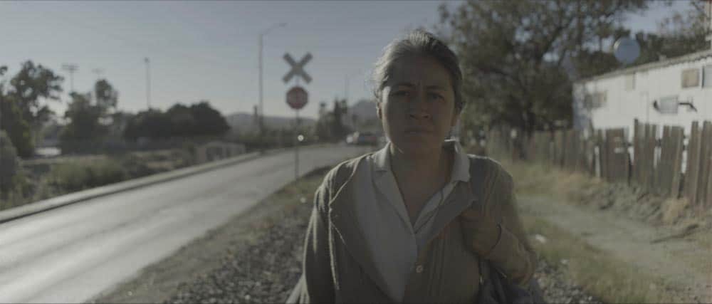 A still of Magdalena walking on the roadside in Identifying Features.