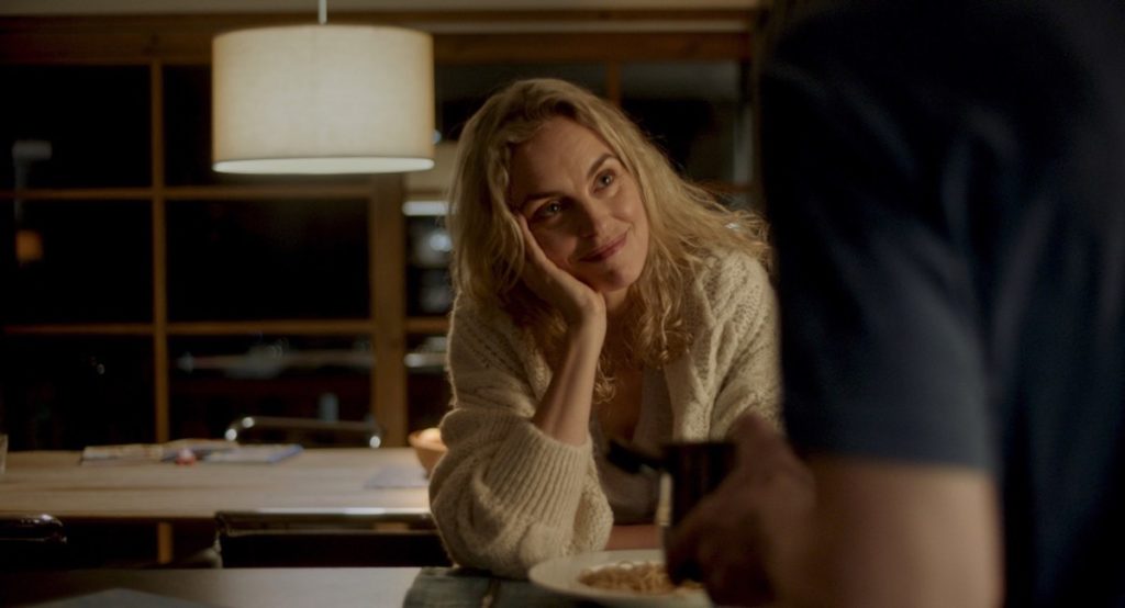 Nina Hoss stars as Lisa in My Little Sister. Courtesy of Film Movement. Lisa is seated at her kitchen island, head resting on her hand, looking up at her husband, whose arm and shoulder can be seen in the right side of the frame.