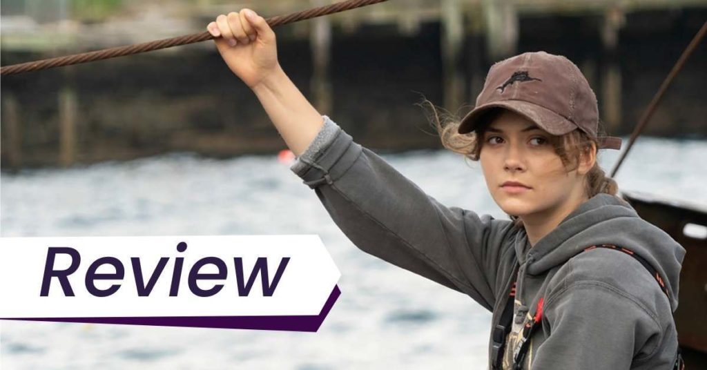 A young woman sits on a boat in this still from CODA. The text on the image reads, 'Review'.