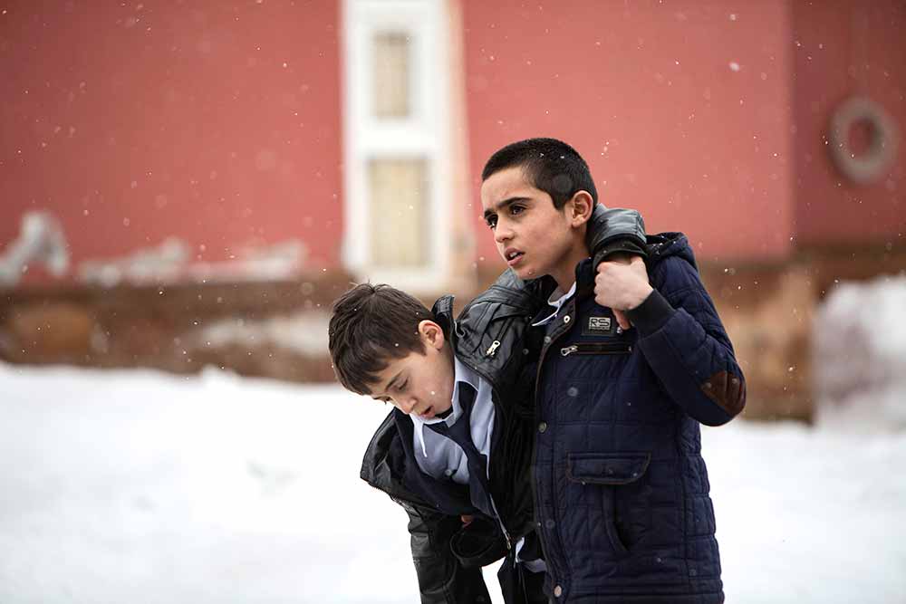 A young boy helps carry another young boy through the snow in Brother's Keeper, one of the best films of Berlinale 2021.