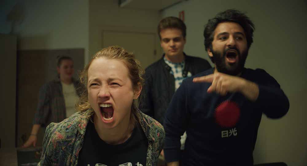 A young woman in a hospital ward screams toward the camera, supported by a man next to her who point in her direction, in Ninjababy.