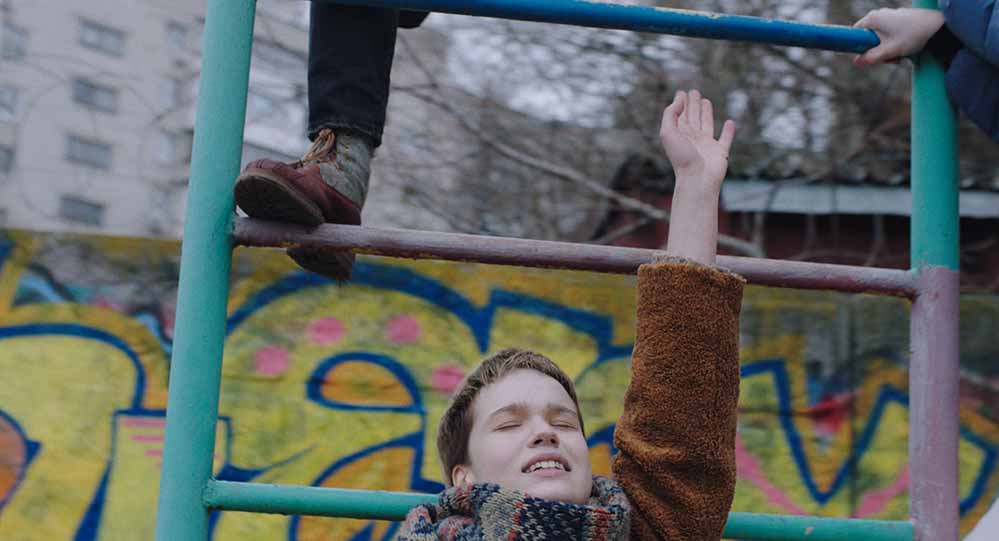 A teenage girl reaches up onto a set of monkey bars in Stop-Zemlia, one of the best films of Berlinale 2021.
