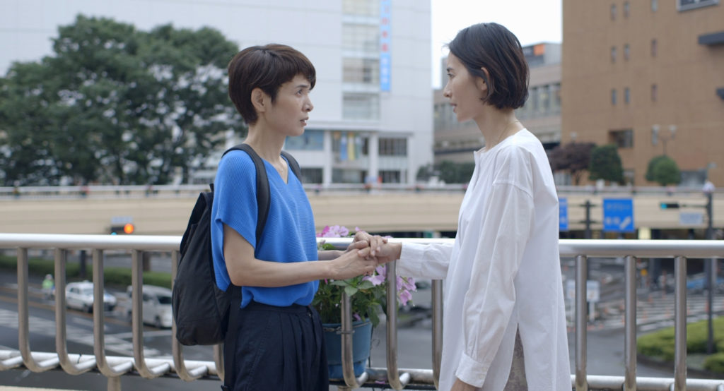 Two middle-aged women face each other by the rail of a train station in Ryûsuke Hamaguchi's Wheel of Fortune and Fantasy.