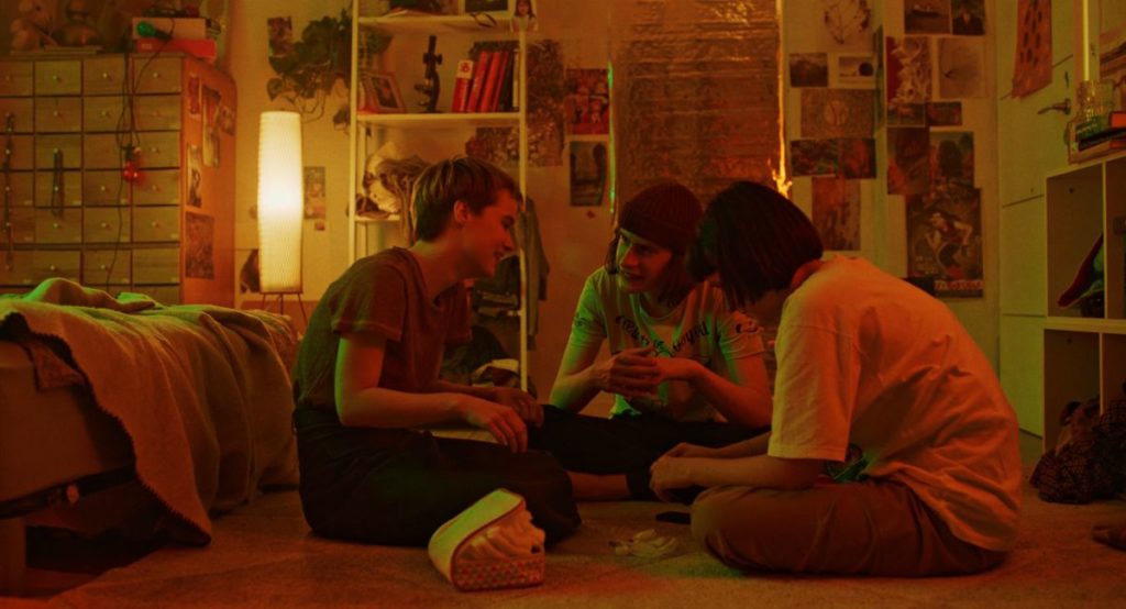 From left to right: Masha (Maria Fedorchenko), Senia (Arsenii Markov), and Yana (Yana Isaienko) hang out in Masha's room in Stop-Zemlia, directed by Kateryna Gornostai, which premiered at the Berlinale 2021.