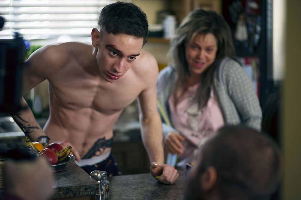 A mid shot of Théodore Pellerin in Chien de Garde. He is topless and leaning over a countertop, in a state of physical tension.