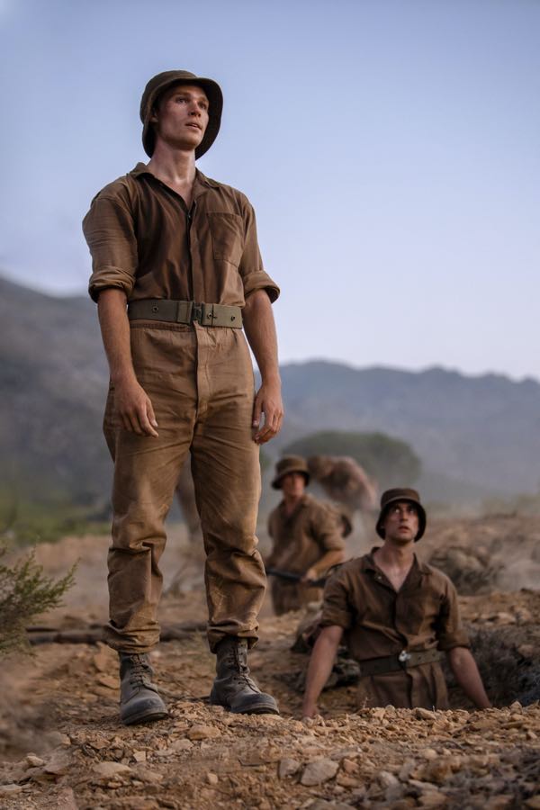 Kai Luke Brummer as “Nicholas” in Oliver Hermanus’ MOFFIE. Courtesy of IFC Films. An IFC Films release. Nicholas is standing next to the trench he has dug, with Stassen in the background.