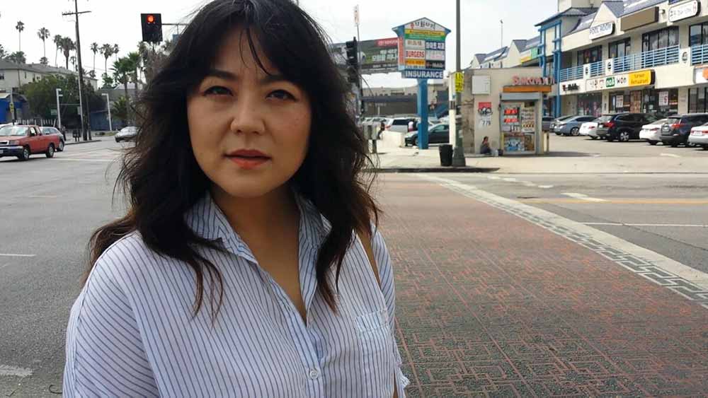 A woman looks at the camera with confused concern in Murder Death Koreatown.