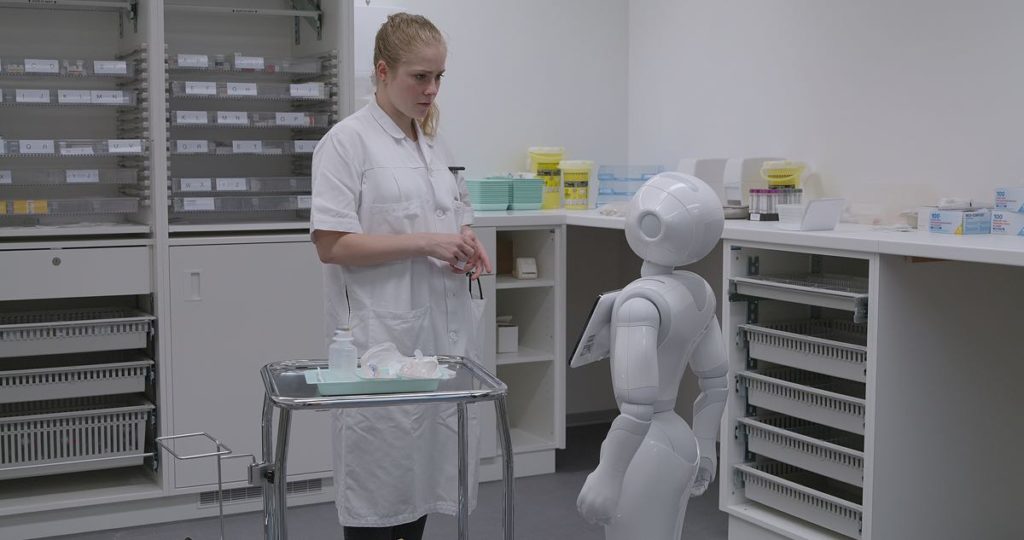 Still from Marie-Eve Hildbrand's Les Guérisseurs in which a medical student checks the medication dosage with the robot assistant. The film premiered at Visions du Réel 2021 in the National Competition.