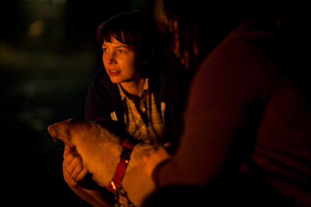 A still from Wendy and Lucy, in which Wendy and her dog Lucy sit by a campfire. The film was based on a short story by Jon Raymond.