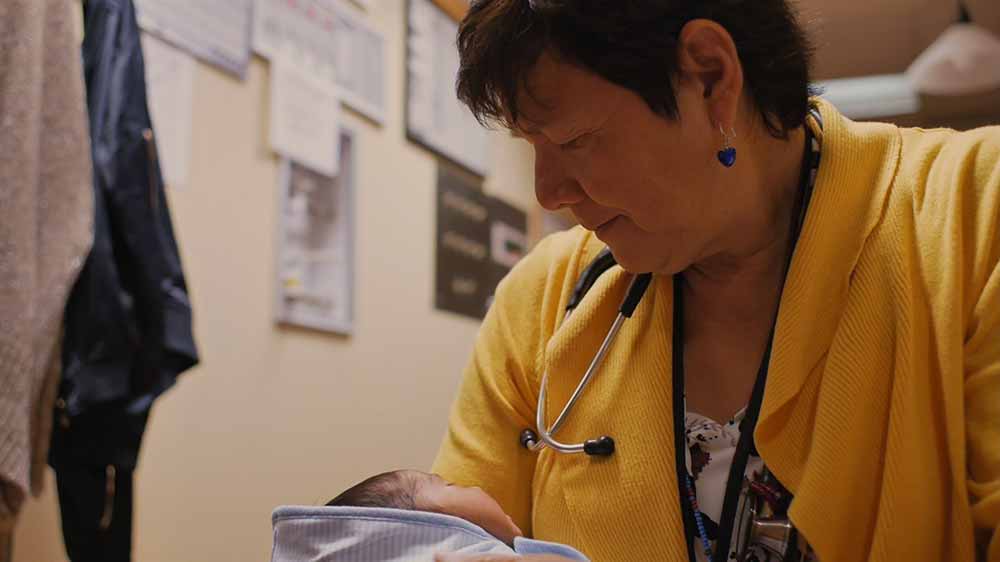 A woman cradles a newborn baby in Kímmapiiyipitssini: The Meaning Of Empathy, one of the best films of HotDocs 2021.