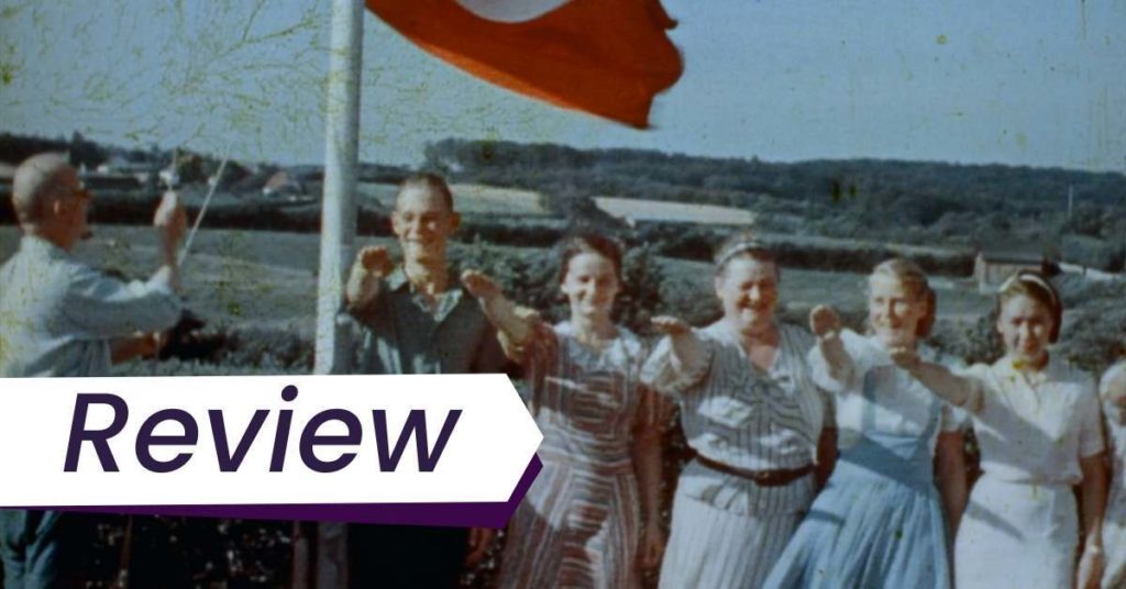 Still from a home video taken during the Third Reich in Luke Holland's documentary Final Account. On a summer day, five young people smile while giving the Third Reich salute while standing under a red Nazi flag.