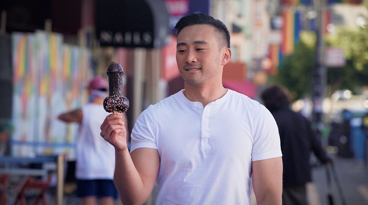 Still of director Alexander Liu holding a penis-shaped dessert in A Sexplanation