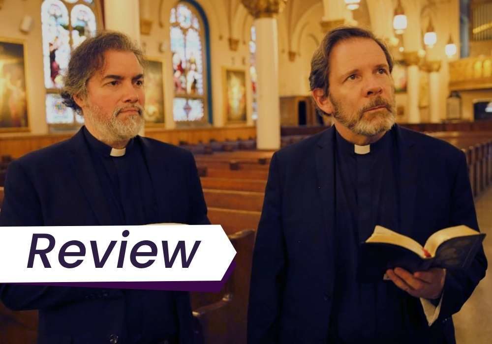 A still from Scenes from an Empty Church in which two priests stand side by side in their church, one holding a bowl, the other a bible. The text on the images reads, 'Review'.