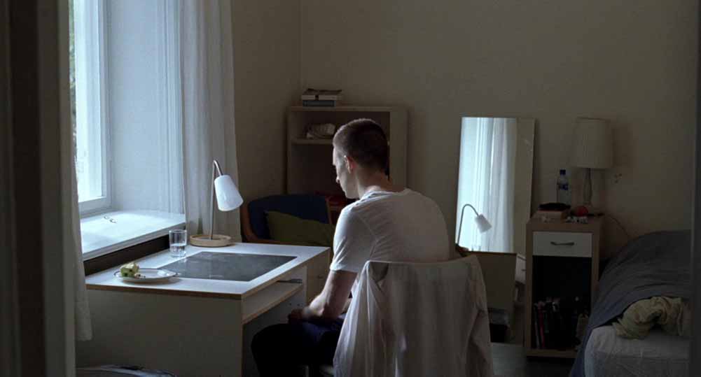 A still from Oslo, August 31st featuring Jørgen Stangebye Larsen's work on Anders's room at the rehab centre, which is bare and white, with a mirror standing by the wall and a few personal affects scattered around.